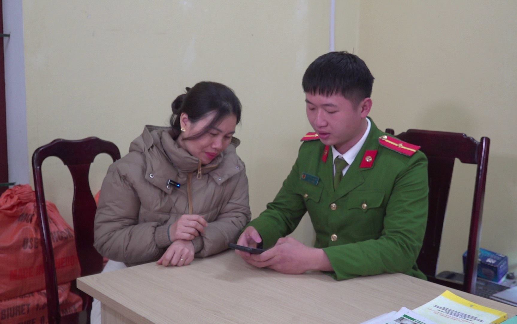 Can bo Cong an thi tran Lang Chanh huong dan nguoi dan kich hoat tai khoan dinh danh tren dien thoai. Anh: Quach Du