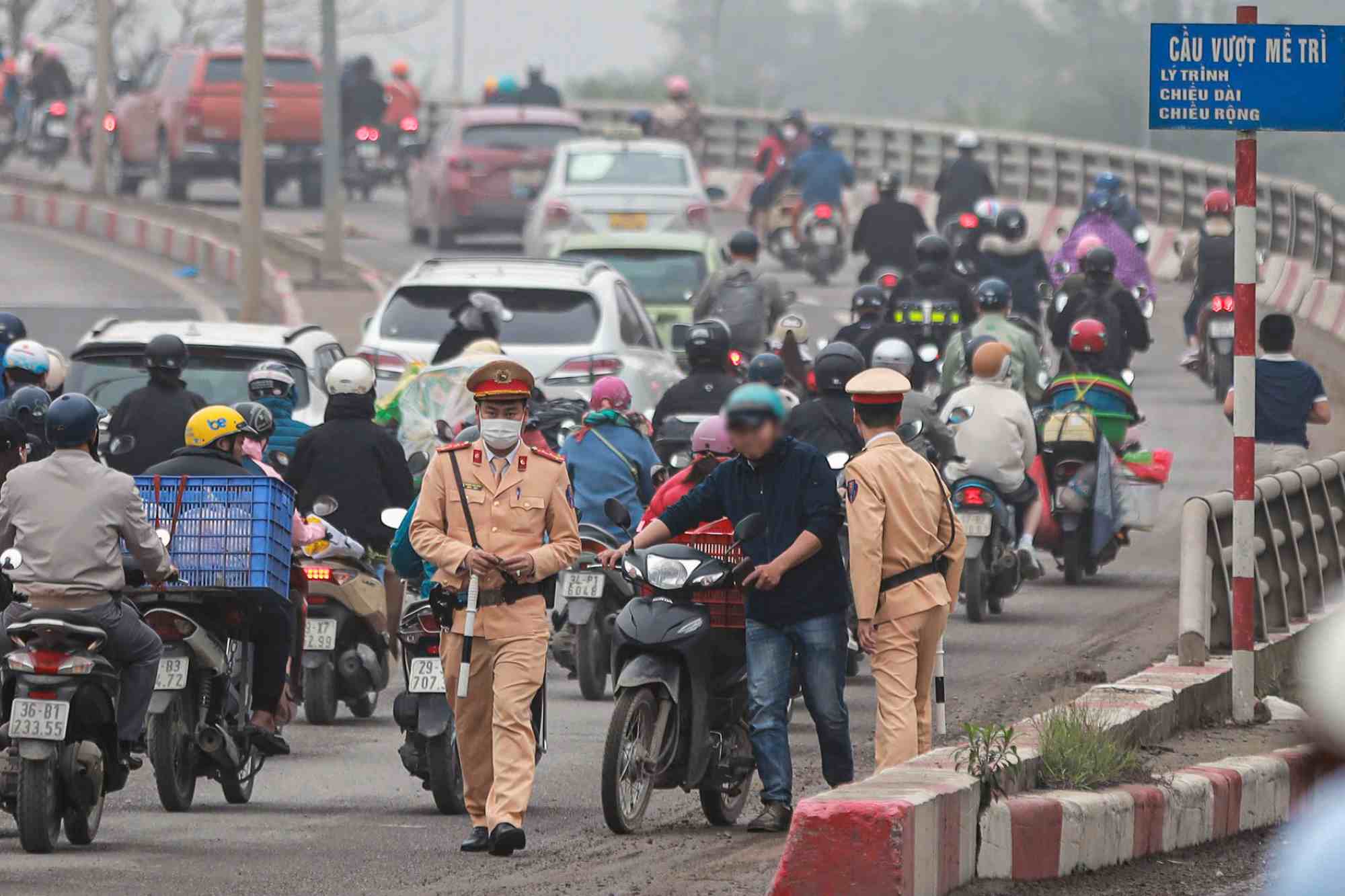 Traffic police handle motorbikes going in the wrong direction at the foot of Me Tri overpass. Photo: The Ky