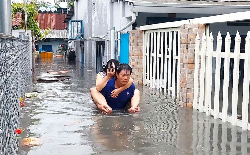 People carrying each other to run through floodwaters at the foot of Go Dua overpass (Tam Binh ward, Thu Duc city, Ho Chi Minh City). Photo: Minh Quan