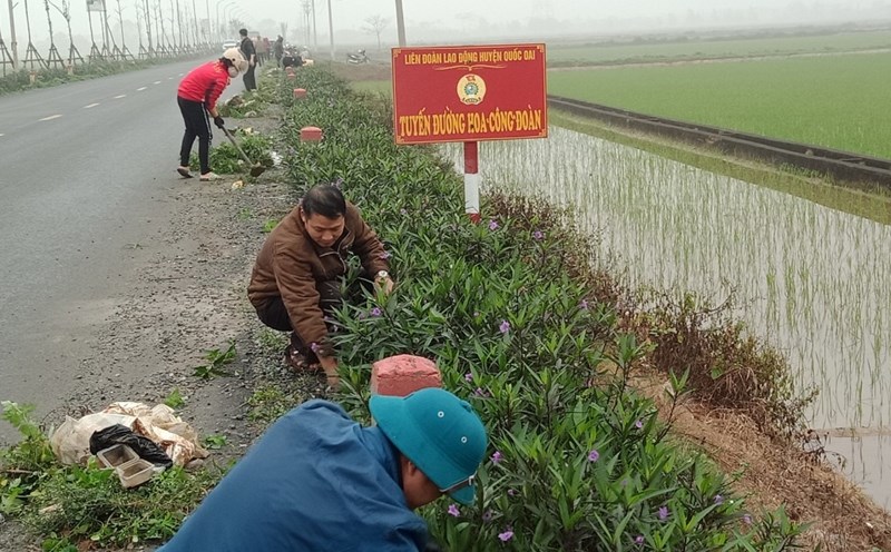 People participate in cleaning and planting flowers on the new rural road in Quoc Oai district, Hanoi. Photo: Q. Bay