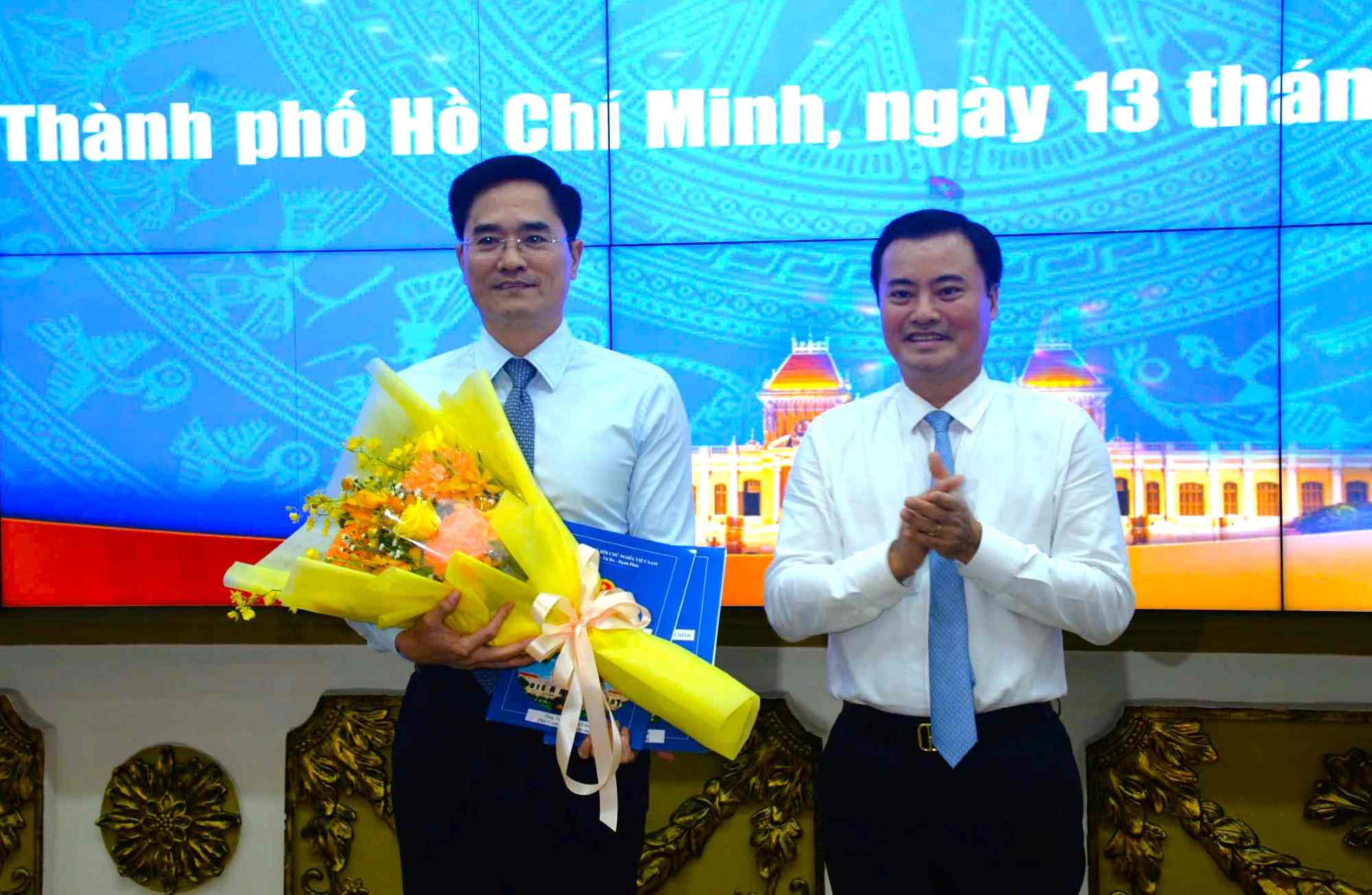Vice Chairman of Ho Chi Minh City People's Committee Bui Xuan Cuong (right cover) presented the decision and flowers to congratulate Mr. Tran Quang Lam. Photo: Ha Khanh