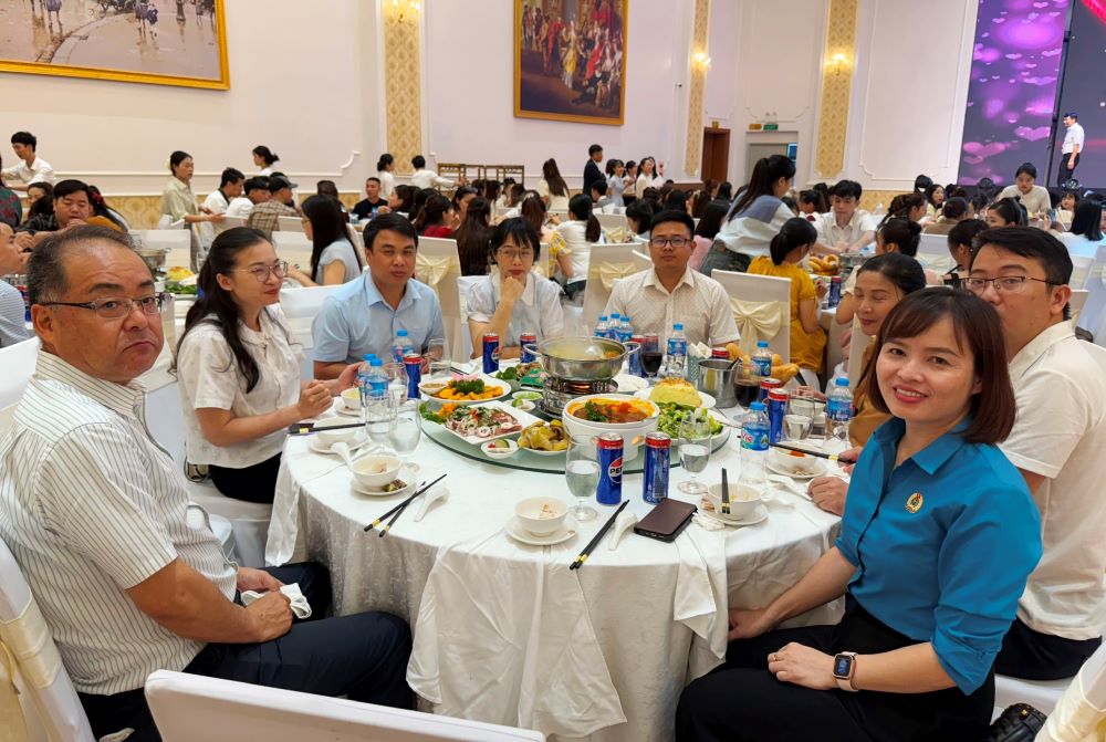 Đại diện lãnh đạo Công ty TNHH Sakurai Việt Nam, Công đoàn Khu Kinh tế Nghi Sơn và các Khu công nghiệp tỉnh Thanh Hóa ăn cơm, trò chuyện cùng công nhân tại bữa tiệc tri ân. Ảnh: Quách Du