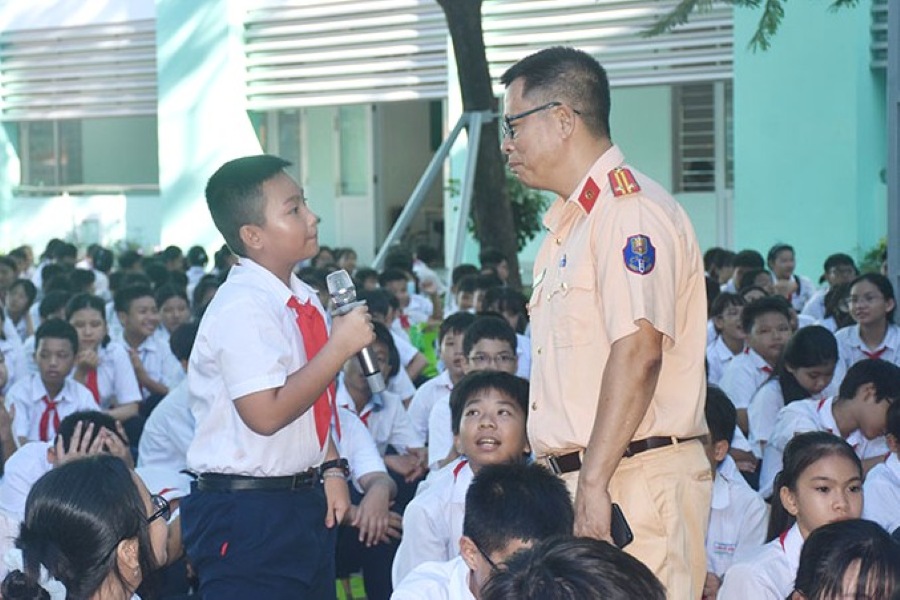 Cán bộ Cảnh sát giao thông trao đổi với các em học sinh trong buổi tuyên truyền trật tự an toàn giao thông. Ảnh: V. Anh