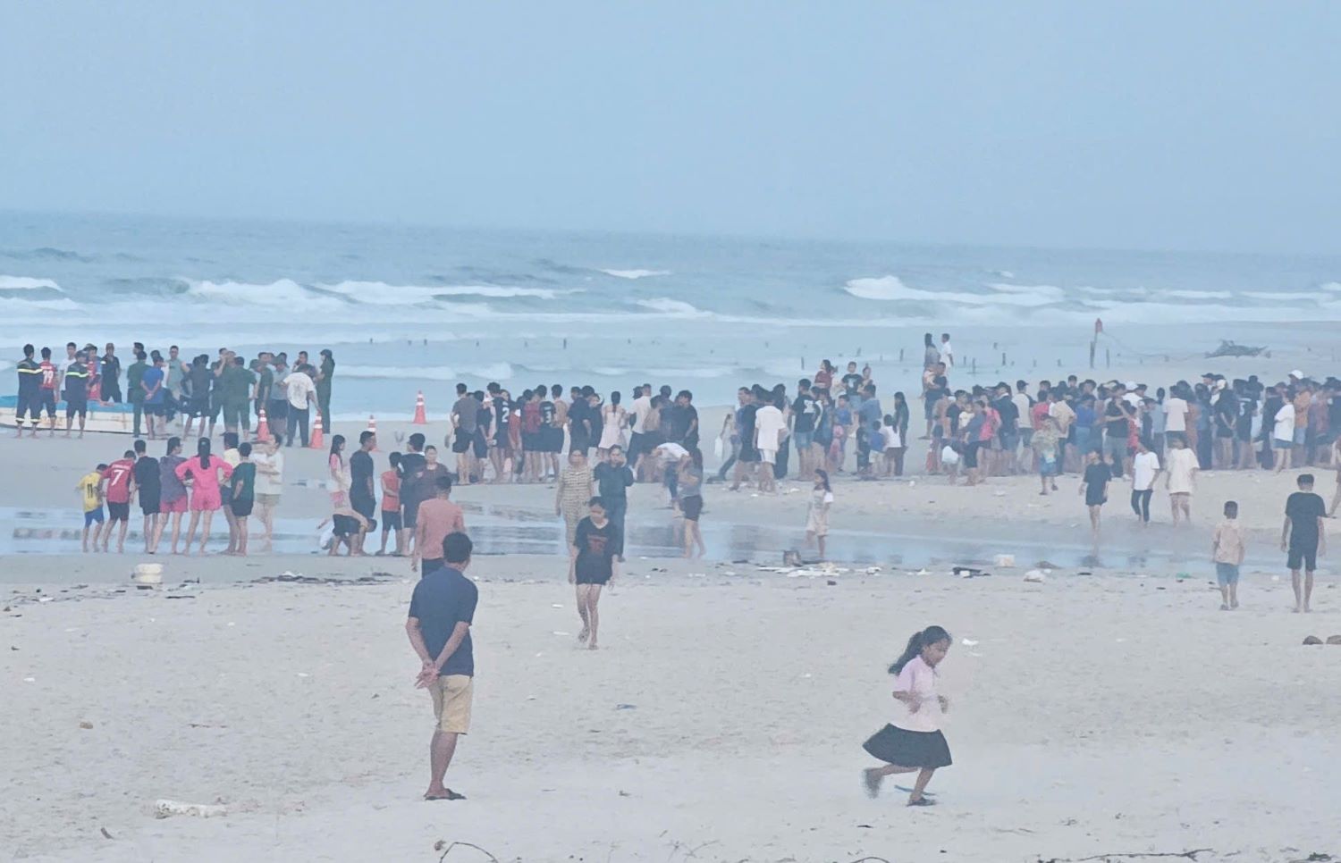 People and authorities gathered near the area where the young man went missing after drowning. Photo: Han Nguyen