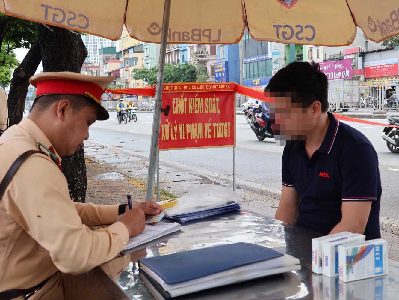 Traffic police handle the driver of a passenger bus that stopped illegally near Giap Bat bus station, May 1. Photo: Hanoi Police