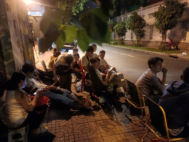 Padres durante la noche esperando frente a la puerta de la escuela primaria para practicar la Universidad de Saigon para comprar documentos de admision para el grado 1 para sus hijos en 2024. Foto: Huyen Trang