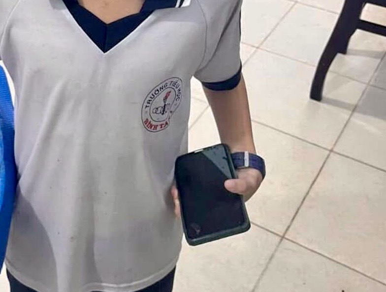Em Tuấn đội mưa mang chiếc điện thoại nhặt được đến công an phường nhờ tìm người đánh rơi trả lại. Ảnh: Công an Bình Tân