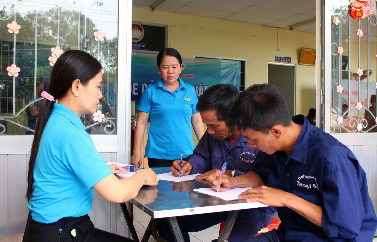 Cán bộ LĐLĐ huyện Thoại Sơn hướng dẫn đoàn viên, công nhân, người lao động làm thủ tục đăng ký khám, tư vấn bệnh, cấp thuốc miễn phí. Ảnh: Thanh Mai