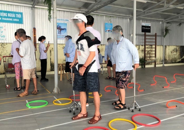 Mot benh nhan duoc thay khop tap phuc hoi tai Khu hoat dong ngoai troi duoi su huong dan cua nhan vien y te. Anh: Song Han