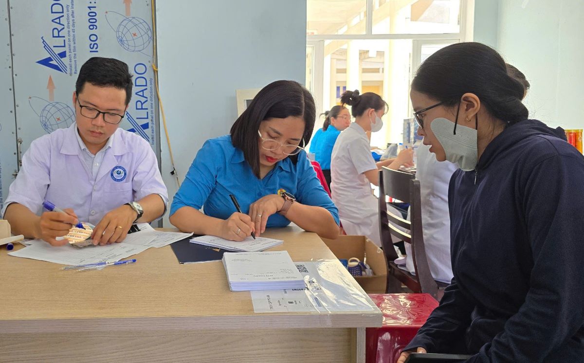 Cán bộ công đoàn cùng cán bộ y tế hướng dẫn người lao động nhận sổ khám bệnh. Ảnh: Hưng Thơ
