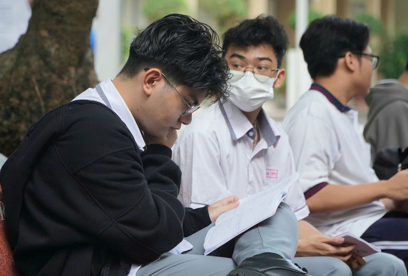 Một số thí sinh tranh thủ ôn lại bài trước lúc bước vào phòng thi. Ảnh: Chân Phúc