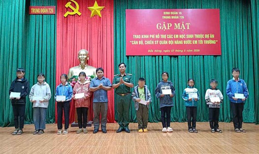 Trung tá Đỗ Văn Tráng - Chính ủy Trung đoàn 726 cùng chính quyền xã Quảng Trực trao kinh phí tặng các em học sinh. Ảnh: Hồng Thắm