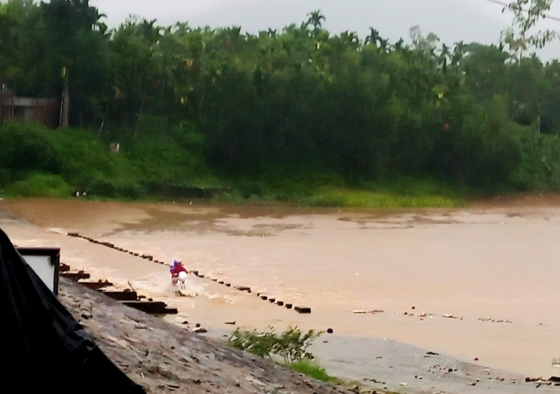 Nuoc song Tien o huyen Tien Phuoc, Quang Nam len nhanh. Mot nguoi dan voi va bang qua cau ngap nuoc ve nha. Anh: Tien Phuoc