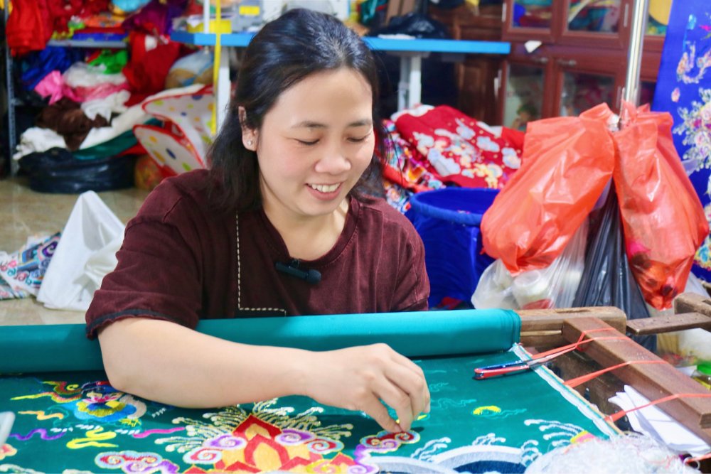 Artisan Pham Thi Pha works hard next to the embroidery frame in her family's workshop. Photo: Quynh Chi