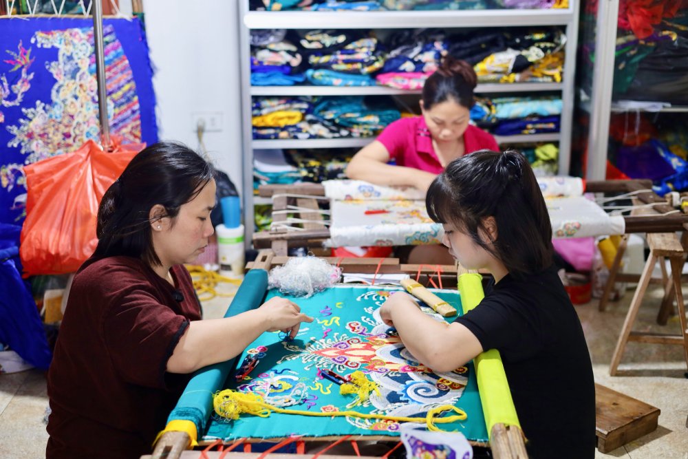 Trong khong gian xuong nho, nghe nhan Pha (ben trai) dang tan tinh day con gai tung duong kim mui chi. Anh: Quynh Chi