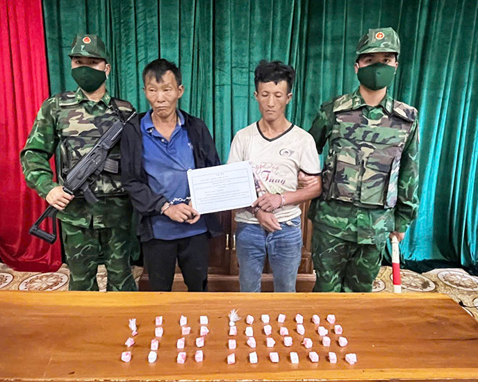 Hai đối tượng Giàng Páo Kỷ (áo đen bên trái) và Tráng A Chù cùng tang vật vụ án. Ảnh: Anh Dũng