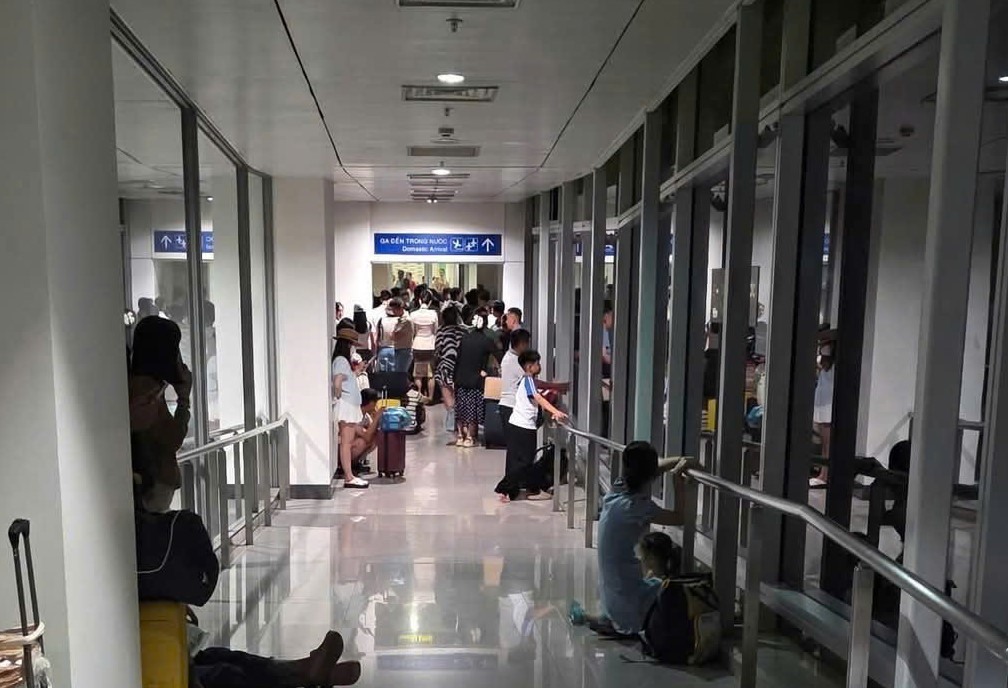 Hành khách đứng trong hành lang ống lồng do cánh cửa dẫn vào nhà ga sân bay Tân Sơn Nhất bị khóa. Ảnh: Q.B

