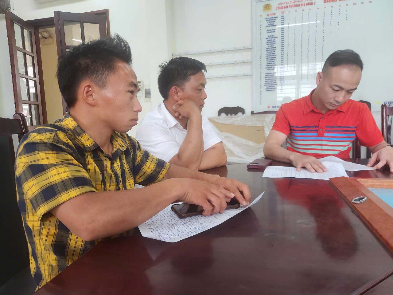 Anh Giàng Hồ (áo ca rô kẻ vàng) đến Công an phường Mỹ Đình 2 trình báo, sáng 16.6. Ảnh: Đặng Tiến 