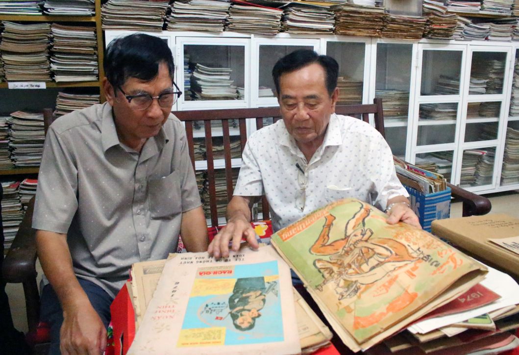 Nha bao Ngo Hoang Van va nha bao Truong Thanh Nha (tu trai sang) xem lai nhung bai viet cua minh tren bao Chien Thang cach day hon nua the ky. Anh: Luc Tung