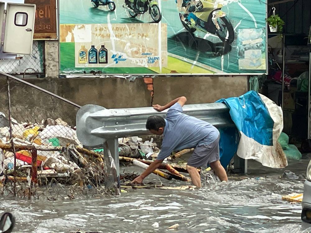 Mua lon rac thai tu cac con kenh tren duong To Ngoc Van troi ra duong. Ảnh: Minh Tam