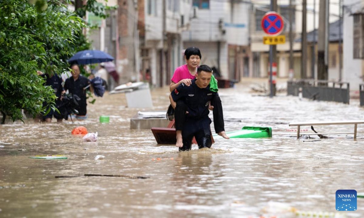 Nhan vien cuu ho giup so tan mot nguoi dan cao tuoi khoi khu vuc bi lu lut o huyen Congjiang, tinh Quy Chau, ngay 24.6.2025. Anh: Xinhua