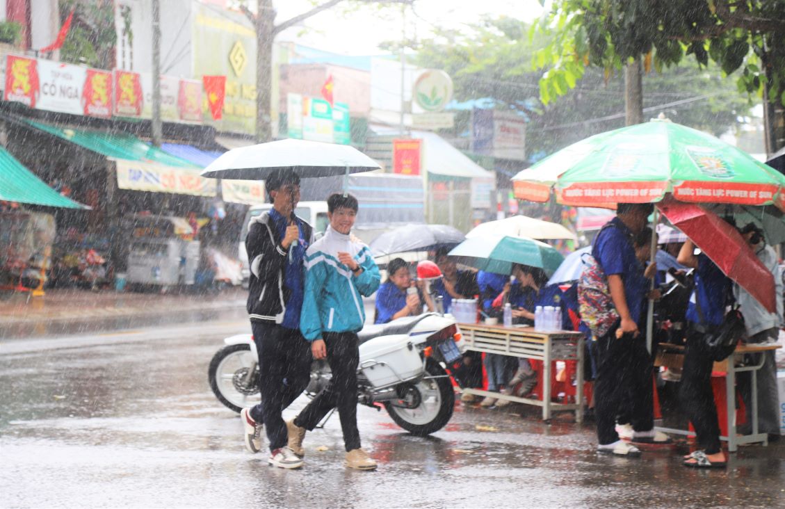 Los voluntarios apoyan a los candidatos a los puntajes de las pruebas bajo la lluvia. Foto: Lam Hong