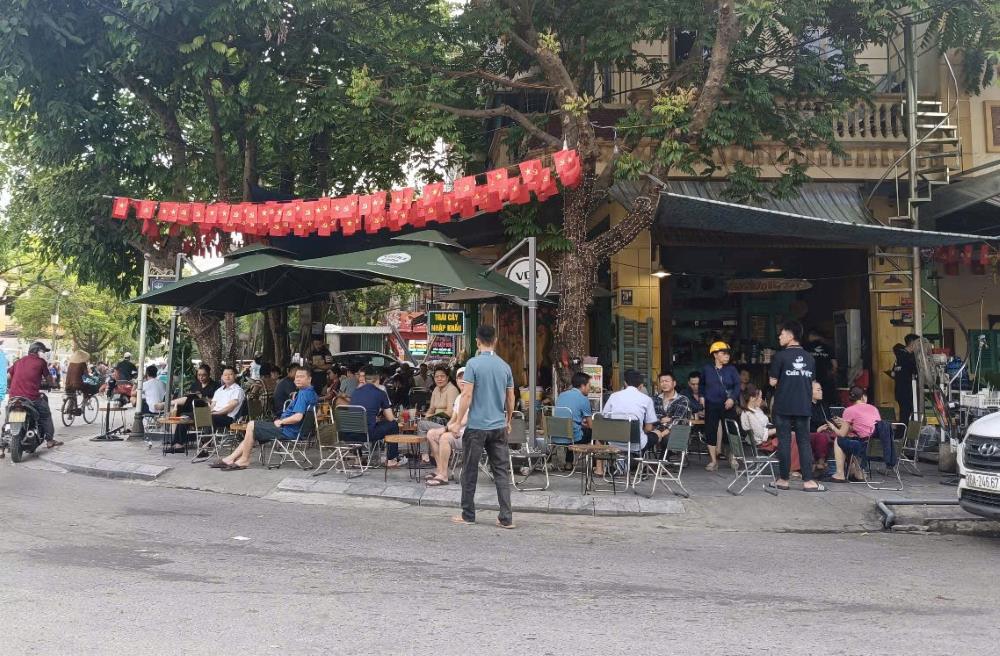 Các phụ huynh ngồi chờ con tại quán nước, gần điểm thi Trường THPT Tô Hiến Thành. Ảnh: Quách Du