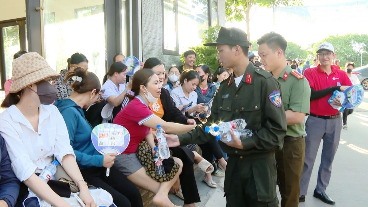 Các chiến sĩ Công an tỉnh Ninh Bình phát nước uống, khăn lạnh, quạt giấy và bánh ngọt cho người nhà thí sinh. Ảnh: Xuân Hùng