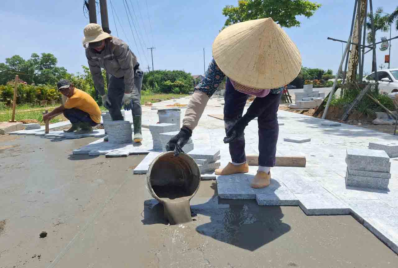 Workers struggle to pave the sidewalk of Xo Viet Nghe Tinh Street in the hot sun. Photo: Tran Tuan.