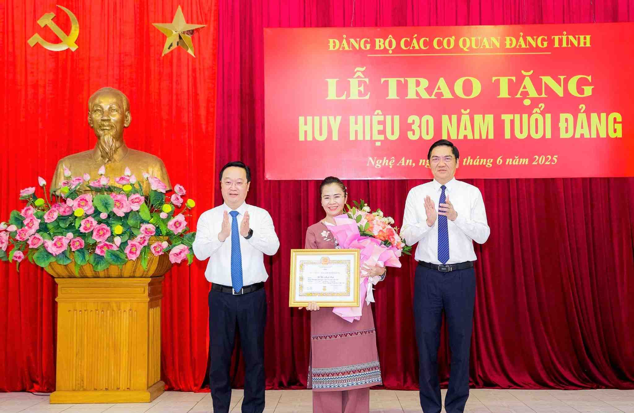 Comrades Nguyen Duc Trung - Secretary of the Provincial Party Committee; Hoang Nghia Hieu - Standing Deputy Secretary of the Provincial Party Committee, Chairman of the Provincial People's Council, Secretary of the Party Committee of Nghe An Provincial Party Agencies - presented the decision, attached the 30-year Party membership badge, presented flowers to congratulate comrade Vo Thi Minh Sinh. Photo: Pham Bang
