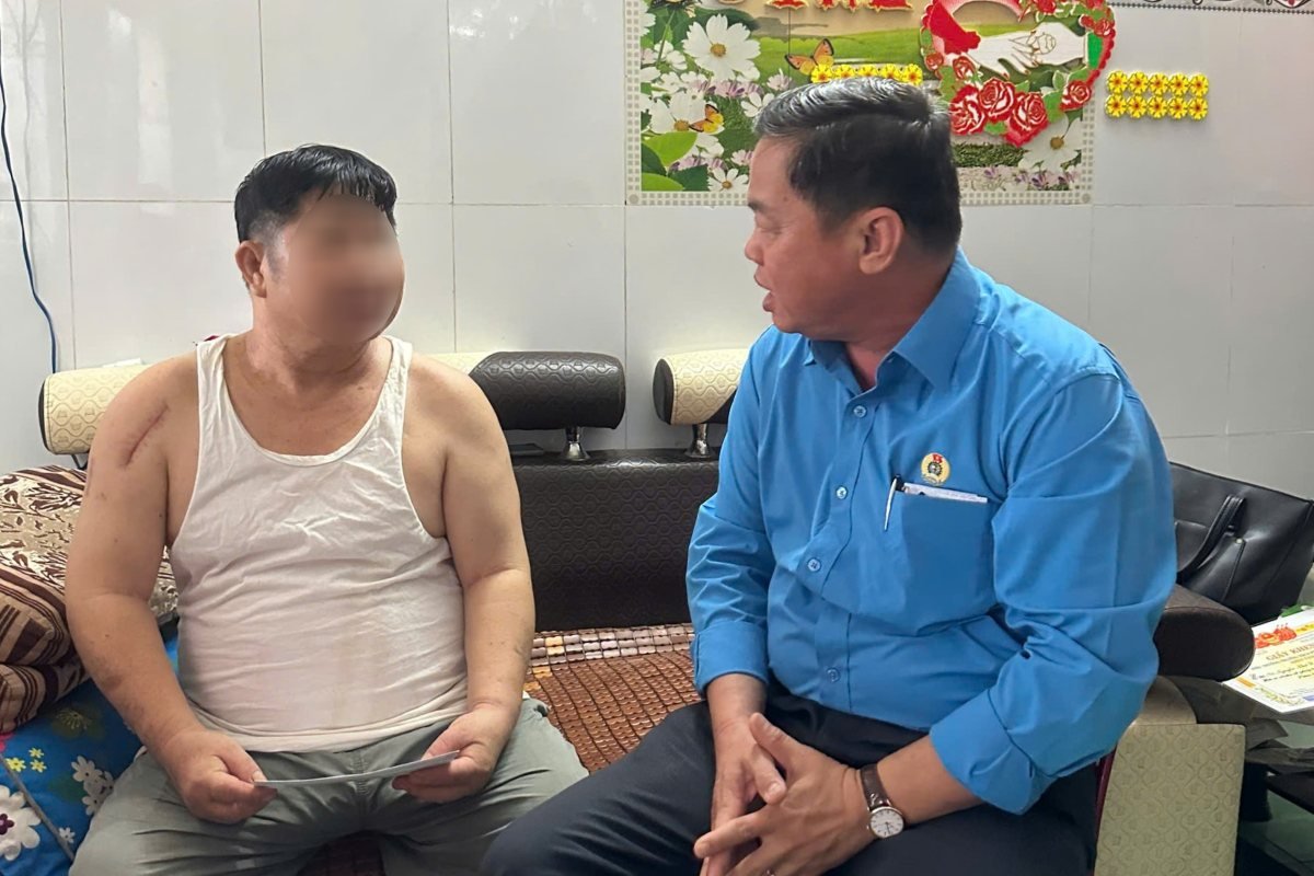 Nguyen Ba Hung 씨(오른쪽)가 집에서 치료를 받고 있는 사고를 당한 조합원을 격려하고 있습니다. 사진: Ngoc Cam