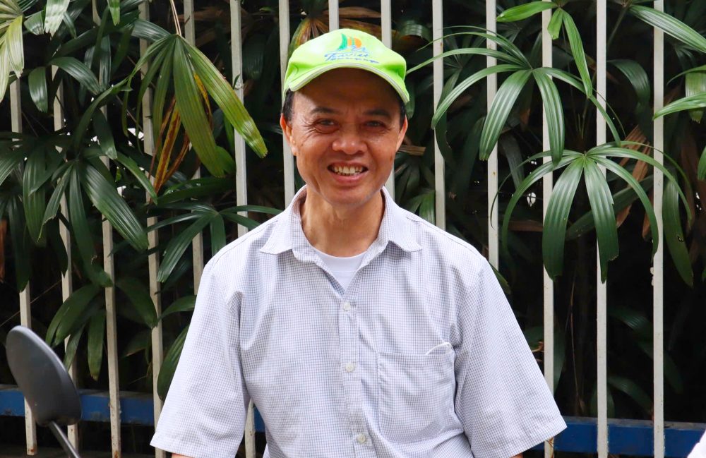 El Sr. Nguyen Tien Loc se sento en la puerta de la escuela esperando que su nieto ingrese al Grado 10. Foto: Huyen Chi