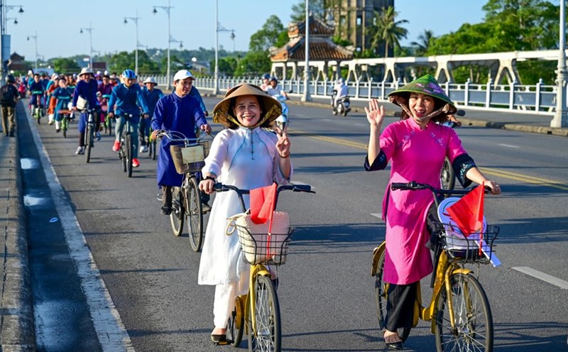 A group of people wearing ao dai cycling to see Hue Street.