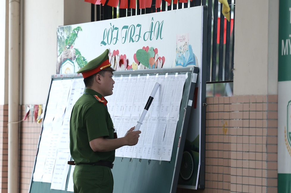 Tai diem thi Truong THCS My Dinh 1, mot phu huynh khong nho phong thi cua con nen nho luc luong cong an tim danh sach de gui do dung vao phong thi. Anh: Hai Nguyen 