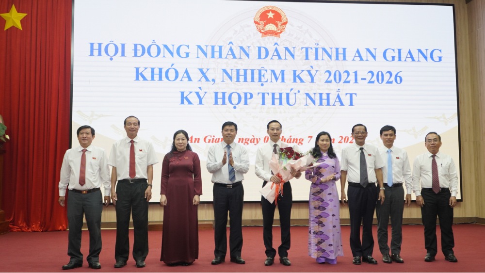 Le secretaire du Comite provincial du Parti d'An Giang Nguyen Tien Hai offre des fleurs pour feliciter le president du Conseil populaire provincial Nguyen Thanh Nhan (entoure de fleurs) et les vice-presidents et chefs des departements specialises du Conseil populaire. Photo : Nguyen Anh