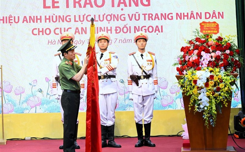 Minister Luong Tam Quang respectfully attaches the title of Hero of the People's Armed Forces to the traditional flag of the Department of Foreign Security. Photo: Ministry of Public Security