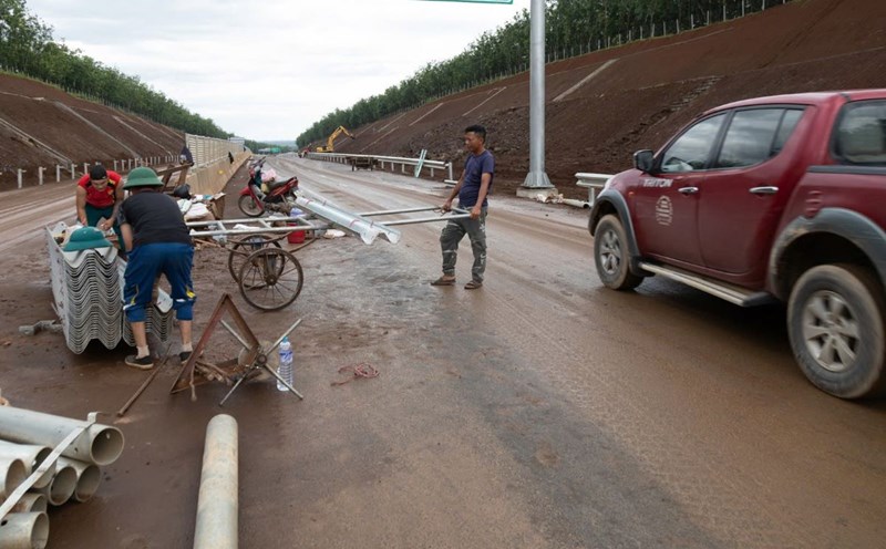 Workers are constructing some items on the highway with many items left on the road, but cars still pass by. Photo: Han Nguyen