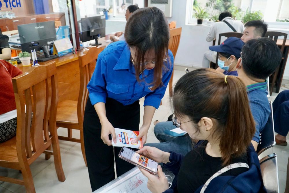Chị Huyền được hướng dẫn sử dụng trợ lý ảo AI để tìm hiểu thông tin về phường mới sau sáp nhập. Ảnh: Minh Tâm