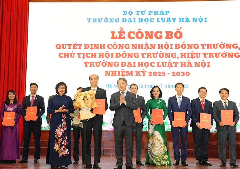 Bộ trưởng Nguyễn Hải Ninh, Thứ trưởng Đặng Hoàng Oanh tặng hoa và trao Quyết định cho Hiệu trưởng Trường Đại học Luật - PGS.TS Tô Văn Hoà. Ảnh: Nhà trường cung cấp 