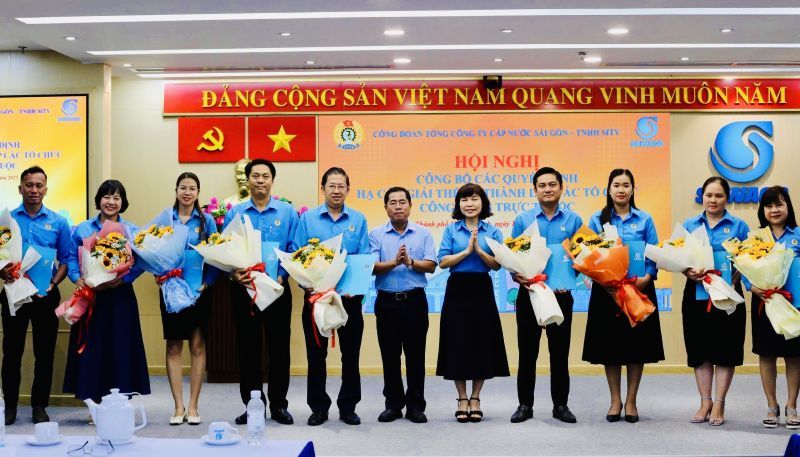 Duong Hong Nhan 씨 - 당위원회 서기이자 사이공 수도공사 - 유한회사 이사회 의장(왼쪽에서 여섯 번째)과 Vu Phuong Thao 씨 - 총공사 노동조합 의장(오른쪽에서 다섯 번째)이 기초 노동조합 대표에게 꽃을 증정하는 결정을 수여하고 있습니다. 사진: Duc Long