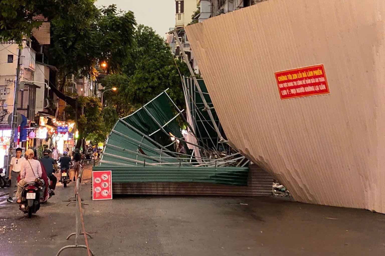 A 6m high corrugated iron fence surrounding the "Squid Protein Hamlet" building was knocked down by the wind on Cau Go Street. Photo: Hoang Hai