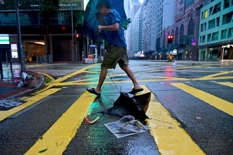 Nguoi di bo tren duong pho o Hong Kong (Trung Quoc) trong gio manh do anh huong cua con bao so 3 o Bien Dong. Anh: Xinhua 