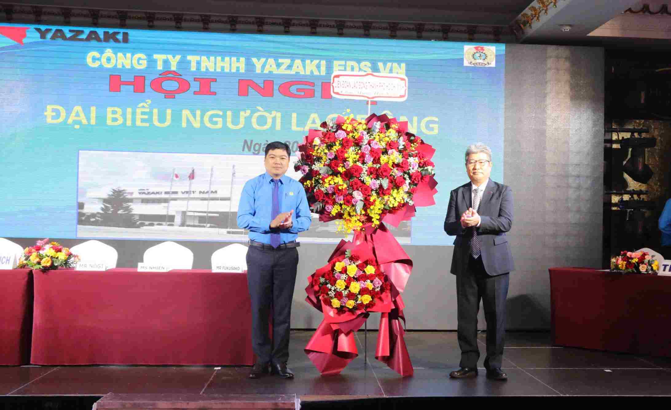 Ông Nguyễn Tấn Đạt - Phó Chủ tịch LĐLĐ TPHCM - tặng hoa chúc mừng hội nghị người lao động của Công ty TNHH Yazaki EDS VN. Ảnh: Dương Bình