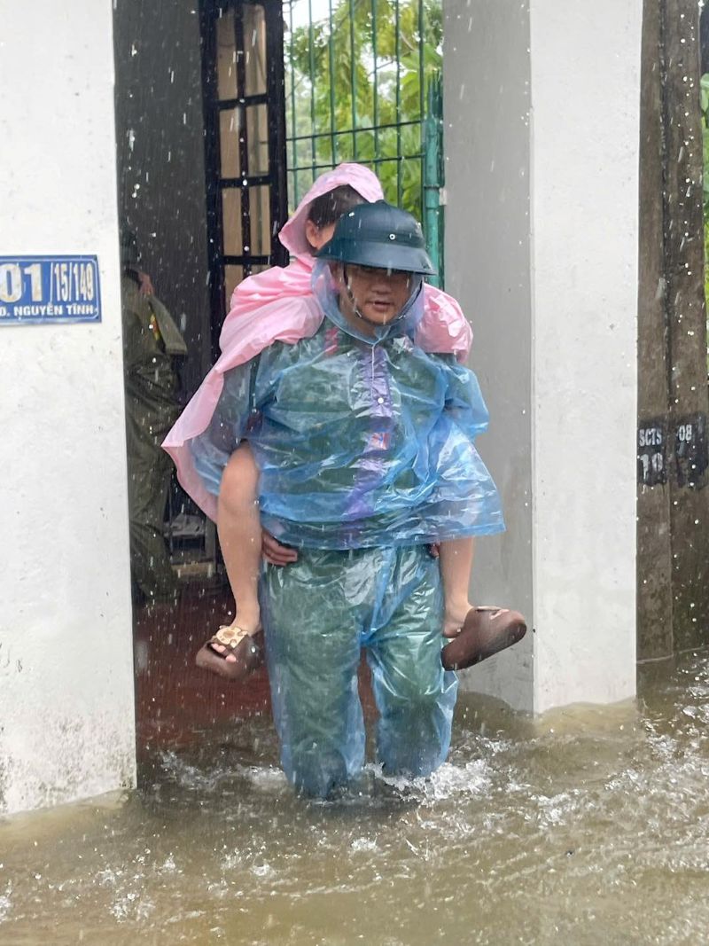 Can bo Cong an phuong Hac Thanh cong chau be ra khoi nha trong vung co nguy co ngap nang. Anh: T.L