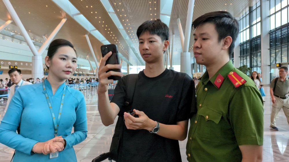 Can bo cong an huong dan nguoi dan “check-in” bang sinh trac hoc tren ung dung VNeID va khuon mat de len may bay, khong can xuat trinh cac giay to, ve may bay nhu truoc - Anh: Anh Tu 
