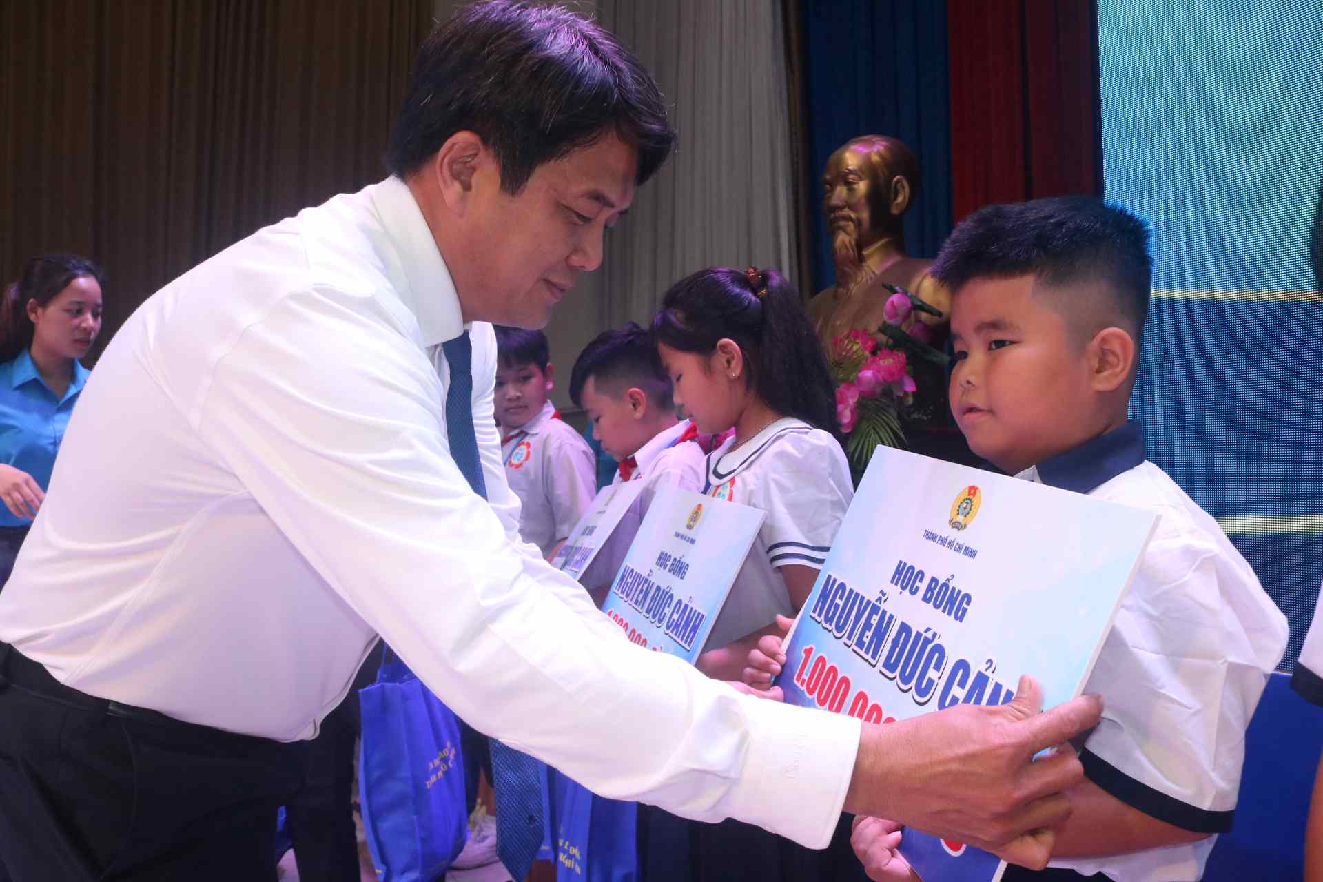 Bui Thanh Nhan 호치민시 노동총연맹 위원장이 어려움을 극복한 노동자 자녀에게 Nguyen Duc Canh 장학금을 수여하고 있습니다. 사진: Dinh Trong