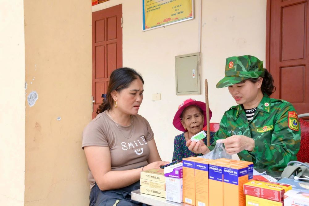 Nu chien si Quan y Bo doi Bien phong phat thuoc cho nguoi dan vung lu. Anh: BDBP