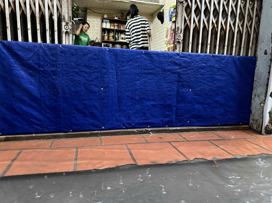 Ghi nhan luc 17h40, khong it ho dan da phai dung bat, chan tam de ngan dong nuoc tran vao nha, co gang bao ve tai san va sinh hoat thuong nhat trong dieu kien vo cung chat vat. Anh: Huyen Trang