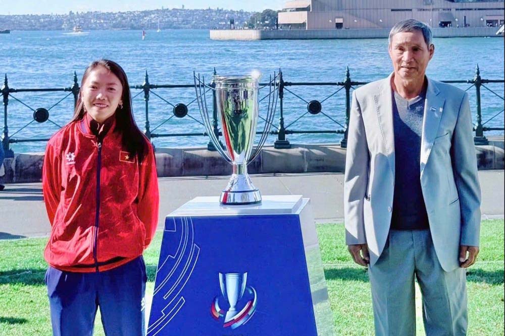2026년 여자 아시안컵 우승팀에게 수여되는 트로피 옆에 있는 Mai Duc Chung 감독과 공격수 Huynh Nhu. 사진: VFF