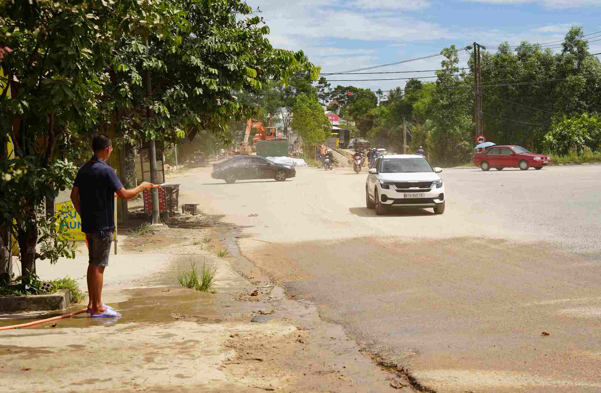 Bụi trắng trời, người dân liên tục tưới nước để giảm bụi. Ảnh: Nguyễn Luân